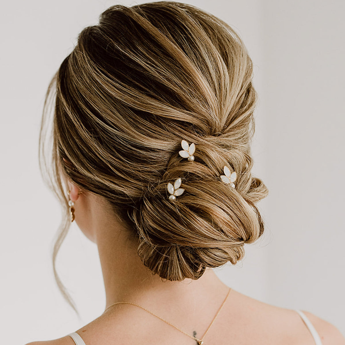 3er Set Braut Haarnadeln Kate in Gold mit white opal Kristallblättern und veganer Perle, getragen in einer eleganten Hochsteckfrisur
