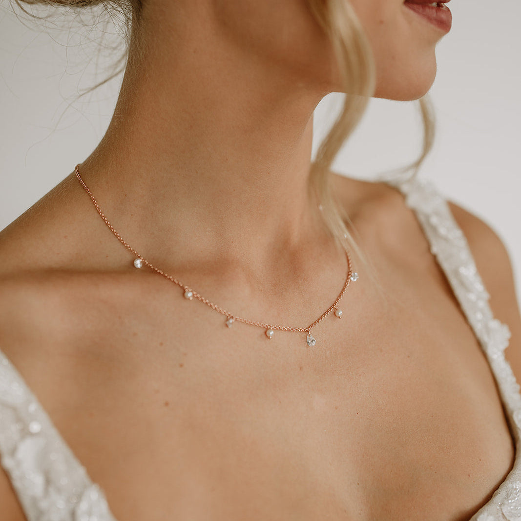 Brauthalskette Amina aus 925 Sterlingsilber 18K rosévergoldet mit veganen Perlen und Kristallen entlang der Kette, am Model getragen in Nahaufnahme