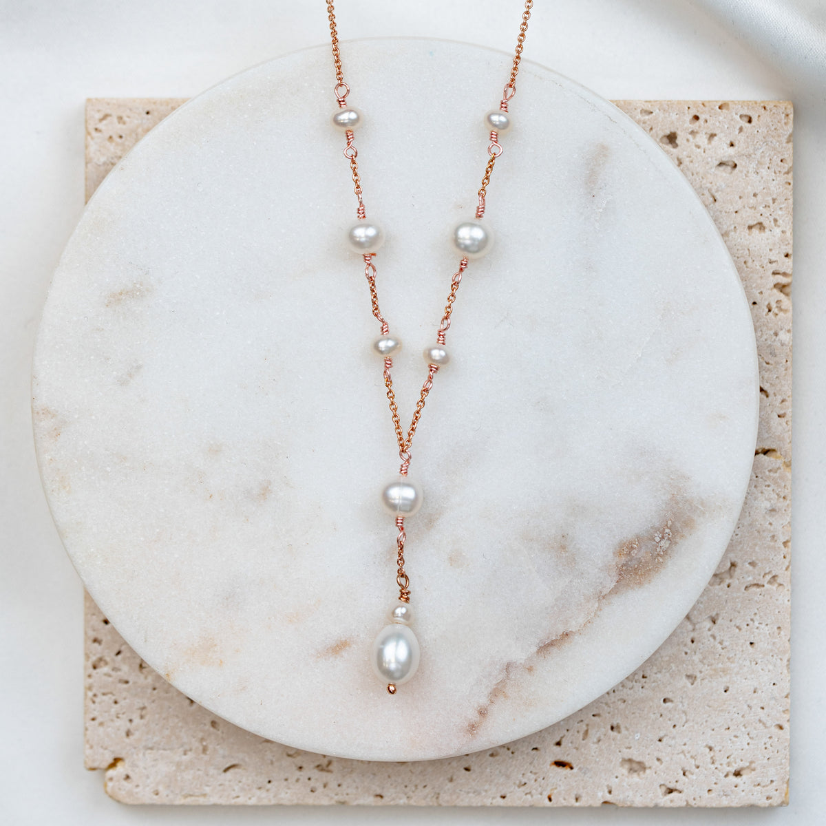 Wunderschöne Braut Y-Perlenkette Joy aus 925 Sterlingsilber 18K rosévergoldet mit Süßwasserperlen, auf Marmorplatte