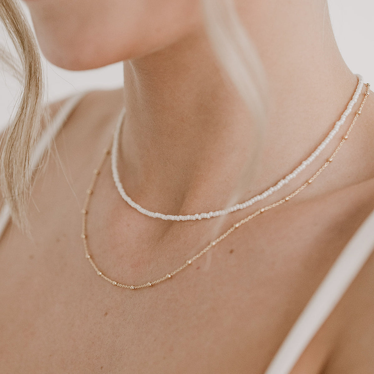 Dezente Brauthalskette Kaya mit kleinen Kügelchen aus 925 Sterlingsilber 18K vergoldet mit Brauthalskette Lina im Layering-Look, am Model getragen in Nahaufnahme
