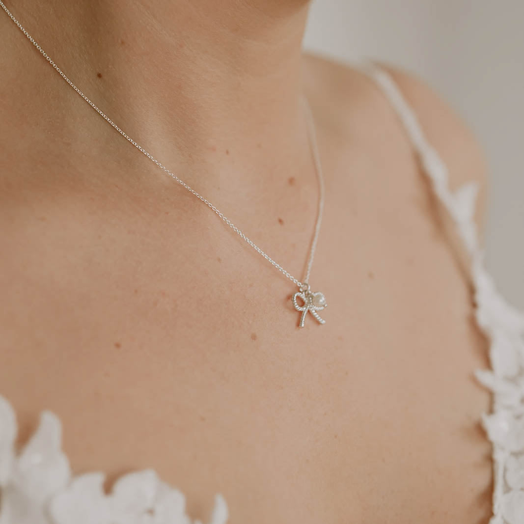 Braut Halskette Pinella aus 925 Sterlingsilber mit Schleife und veganer Perle, Nahaufnahme am Model getragen