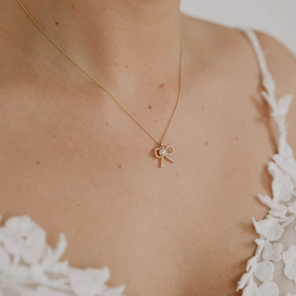 Braut Halskette Pinella aus 925 Sterlingsilber 18K vergoldet mit Schleife und veganer Perle, Nahaufnahme am Model getragen