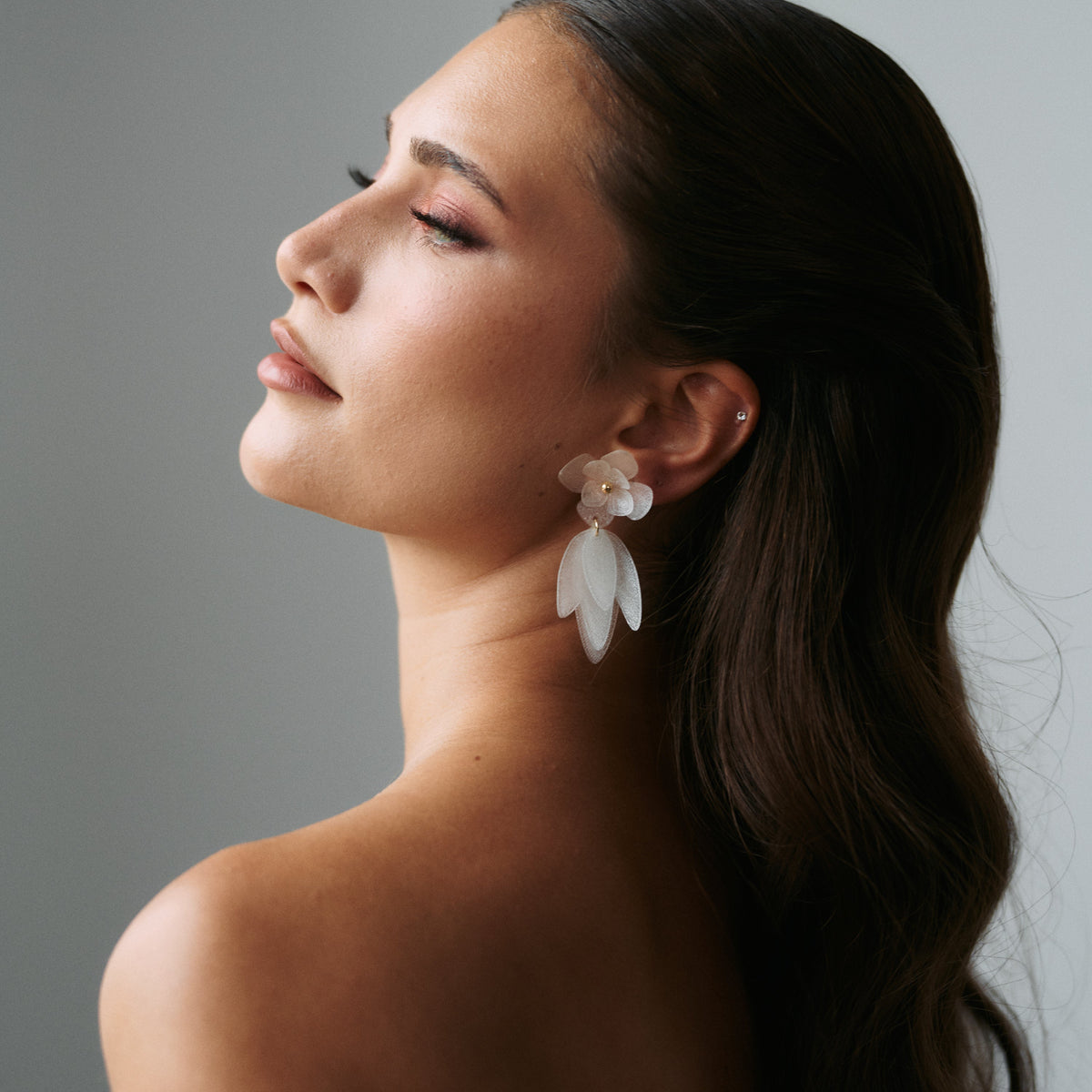 Statement Brautohrringe Chiara mit weißen Blüten aus biobasiertem, nachhaltigen Material, aus 925 Sterlingsilber 18K vergoldet, am Model getragen