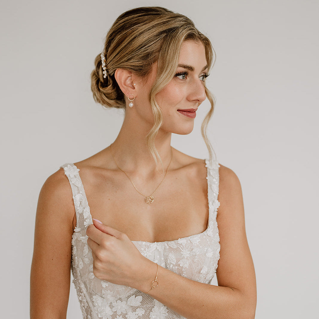Brautkette Toni Trio aus 925 Sterlingsilber 18K vergoldet mit drei ineinander verschlungenen, unterschiedlich gemusterten Ringen mit passendem Brautarmband Toni und Brautohrringen Toni, getragen von einem Model