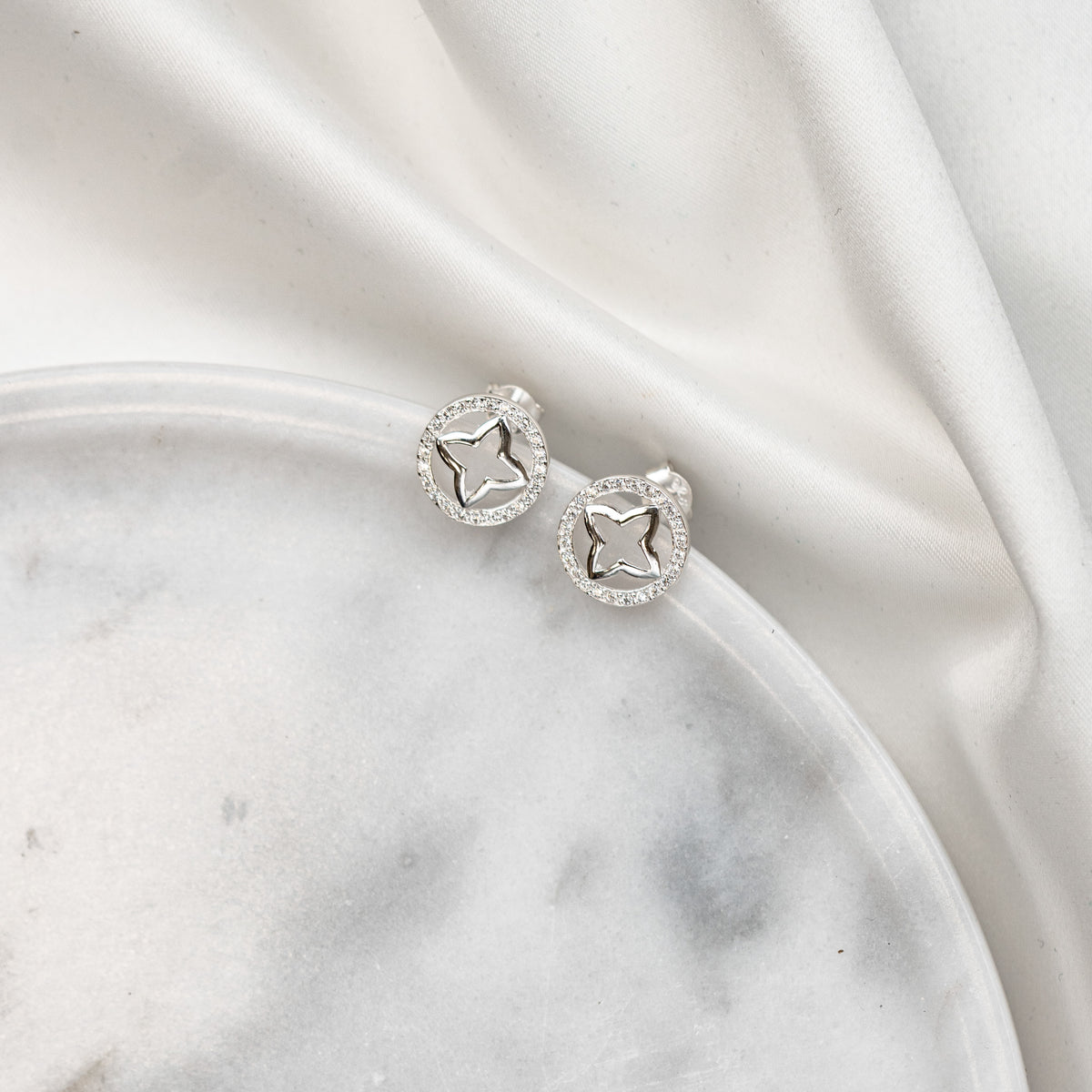 Runder Braut Ohrstecker Olivia aus 925 Sterlingsilber mit Zirkonia Kristallen und Stern in der Mitte, liegend auf einer Marmorplatte