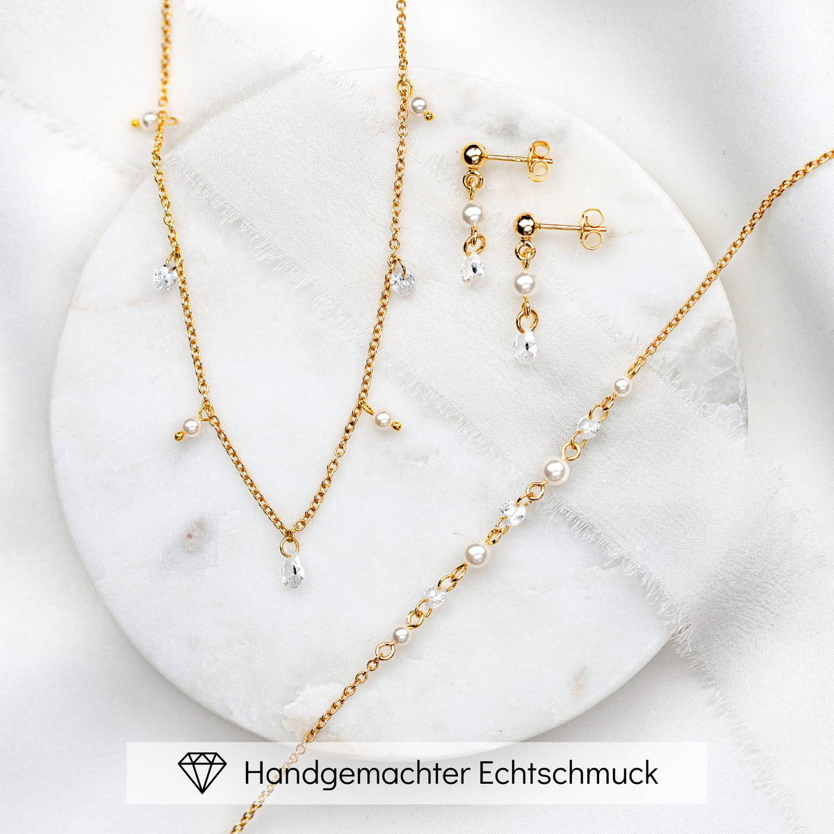 3-teiliges Brautschmuckset Amina aus 925 Sterlingsilber 18K vergoldet – Ohrringe, Halskette und Armband mit veganen Perlen und Kristallen im Wechsel, auf Marmorplatte
