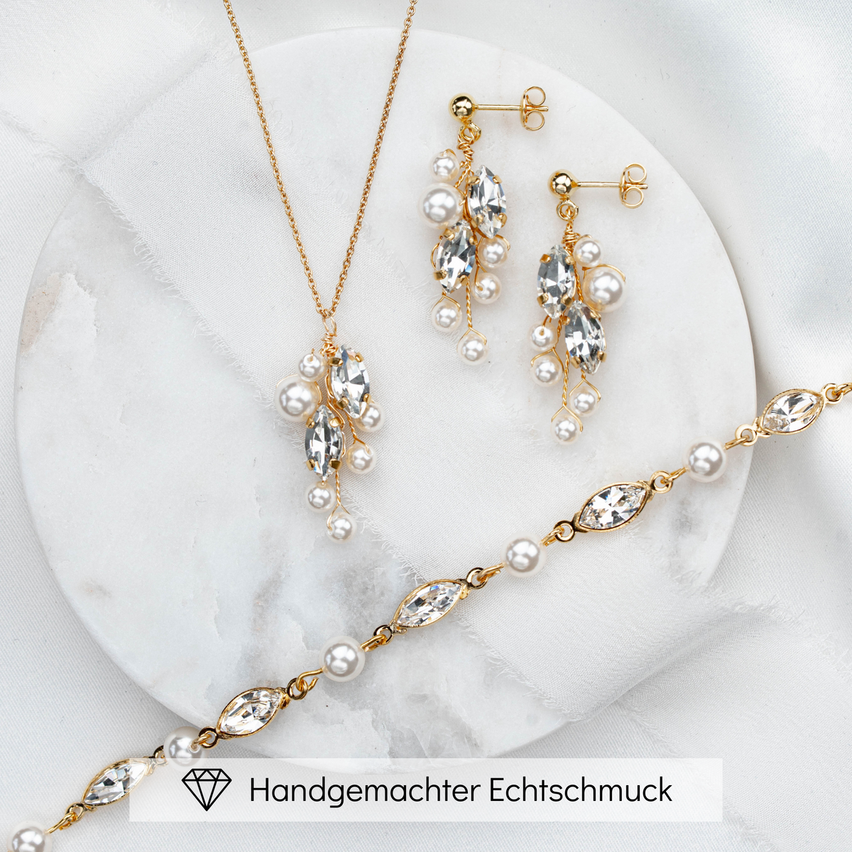 3-teiliges Brautschmuckset Ana aus 925 Sterlingsilber 18K vergoldet – hängende Ohrringe, Halskette und Armband mit veganen Perlen und crystal Kristallen in Blattform, auf Marmorplatte