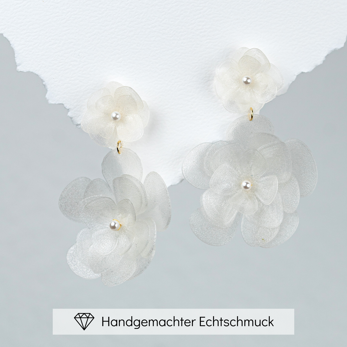 Elegante Statement Brautohrringe aus 925er Sterlingsilber 18K vergoldet mit einer großen und einer kleinen, hängenden Blüte, detailreich dargestellt auf einem weißen Hintergrund.