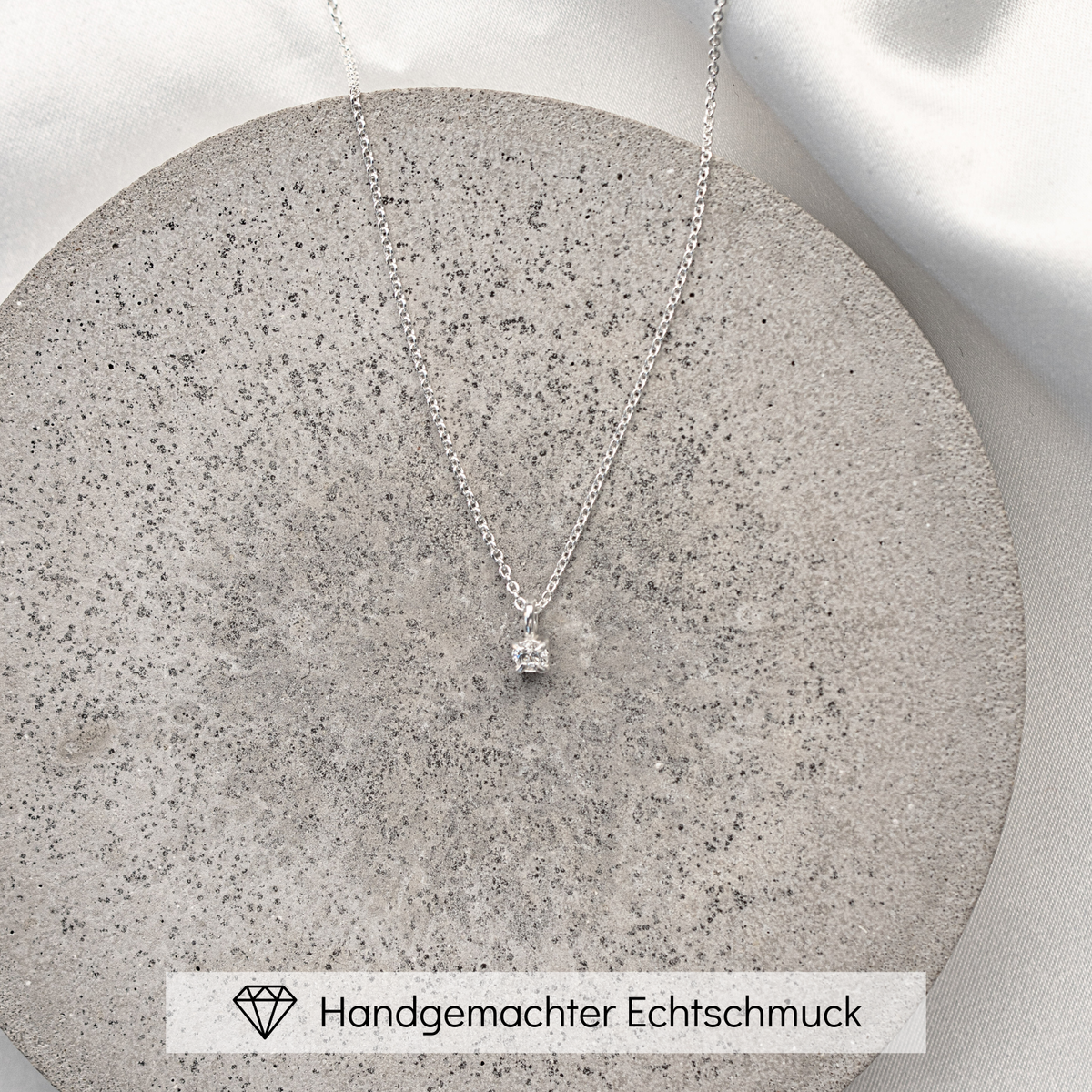 Klassische Brauthalskette Sanna aus 925 Sterlingsilber mit einem Zirkonia Kristall, liegend auf einer Betonplatte