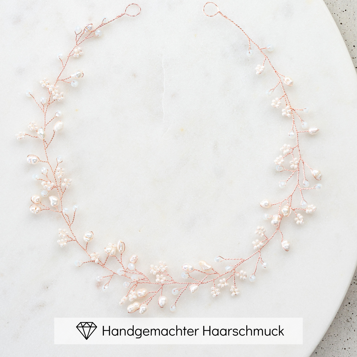 Braut Headpiece Susi in Roségold mit kleinen veganen Perlen, Kristallperlen und echten Süßwasserperlen, liegend auf einer Marmorplatte
