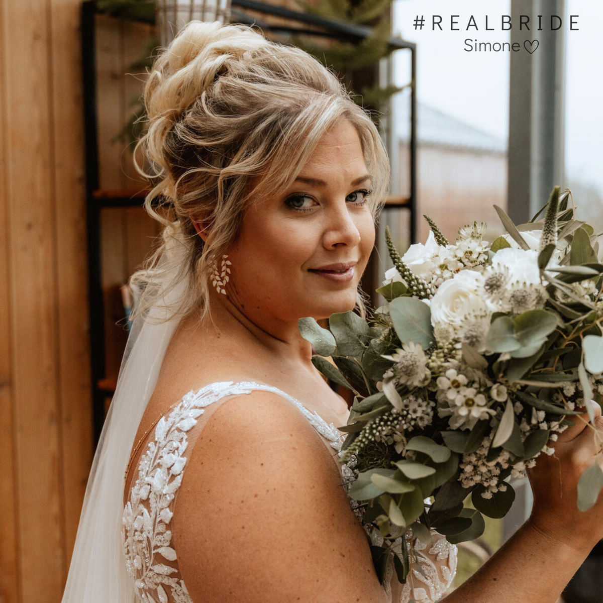 Geschmackvolle hängende Brautohrringe aus 925er Sterlingsilber 18K vergoldet mit ivory farbigen, blattförmigen Ranken, stilvoll getragen von einer Real Bride mit romantischer Hochsteckfrisur und Schleier, harmonisch kombiniert mit einem natürlichen Brautstrauß.