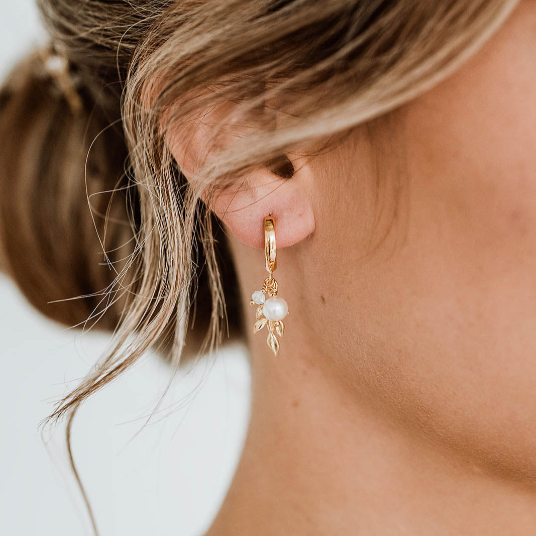 Model trägt Braut Creole aus 925 Sterlingsilber, 18K vergoldet, mit zartem Blattanhänger, weißer Perle und white opal Kristallperle, Nahaufnahme