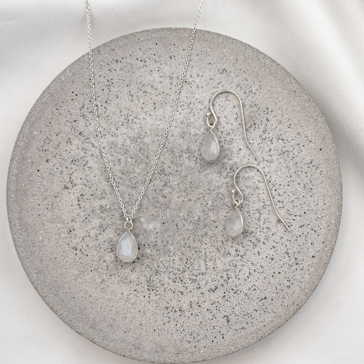 2-teiliges Brautschmuckset Juna aus 925 Sterlingsilber – Halskette und Ohrringe mit echtem Mondstein in Tropfenform, auf Marmorplatte
