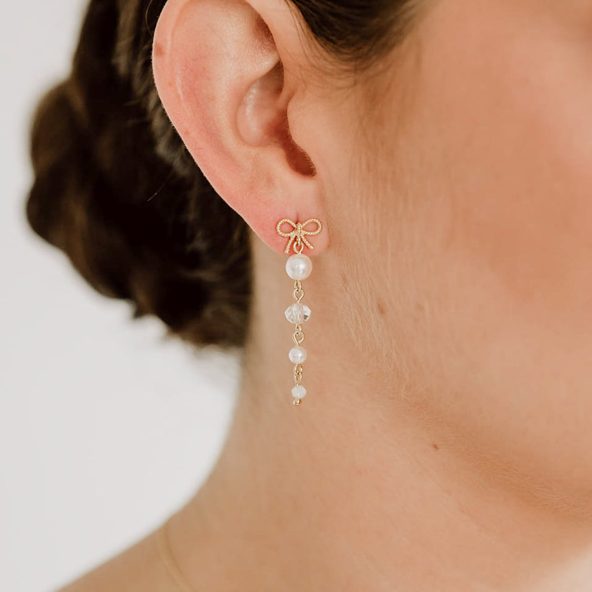 Brautohrringe Pauli mit Schleife aus 925 Sterlingsilber 18K vergoldet, darunter hängend Kristallperlen und veganer Perle, am Model getragen in Nahaufnahme